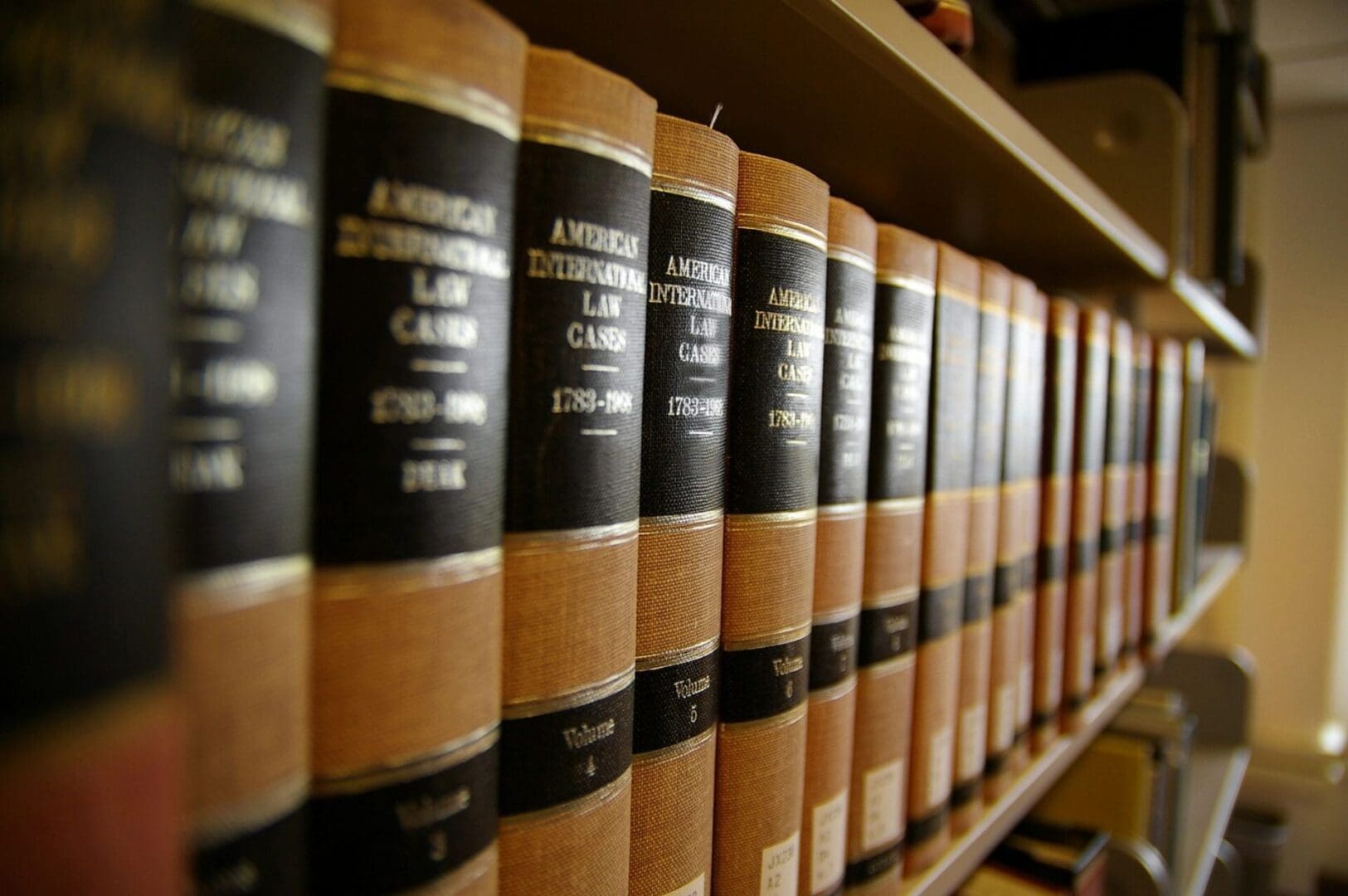 Close-up of a row of legal books on a shelf, titled "American International Law Cases," with various years and volumes visible.